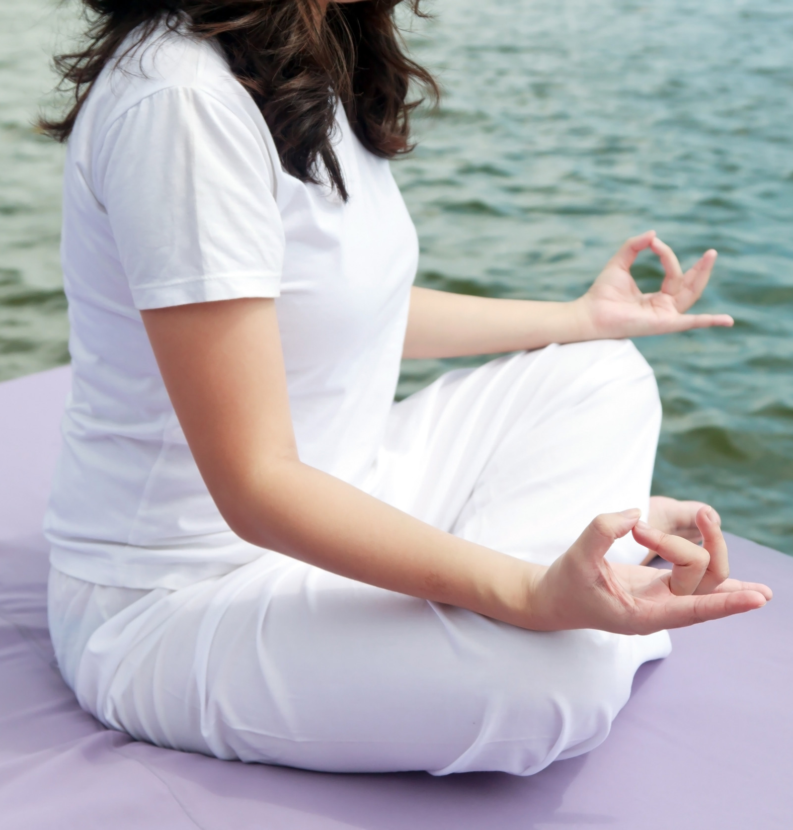 Attractive young asian woman practicing yoga meditation at sunrise by the ocean Attractive young asian woman practicing yoga meditation at sunrise by the ocean