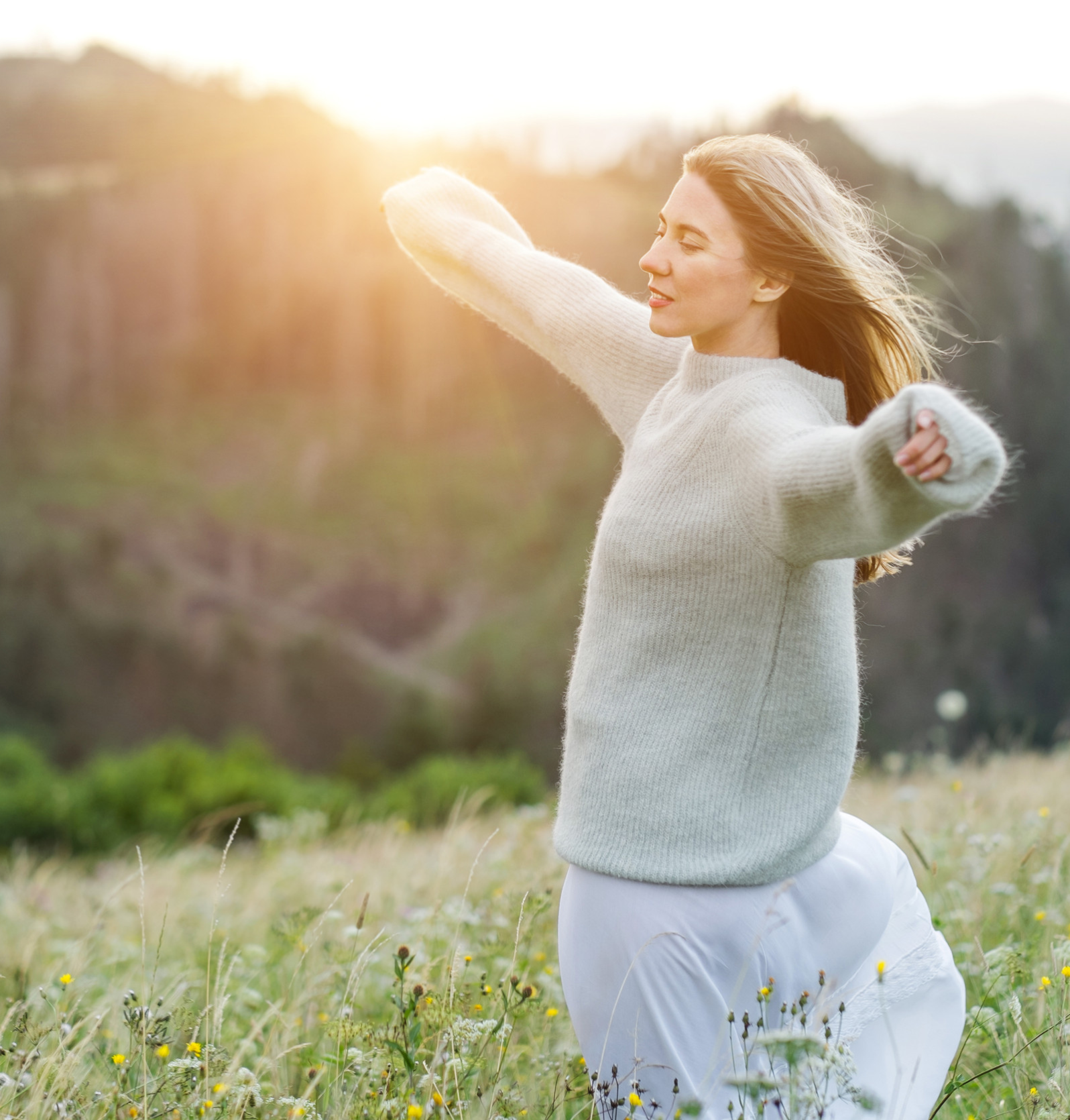 Happy woman enjoying sunset stay on the green grass on the forest peak of mountain Happy woman enjoying sunset stay on the green grass on the forest peak of mountain