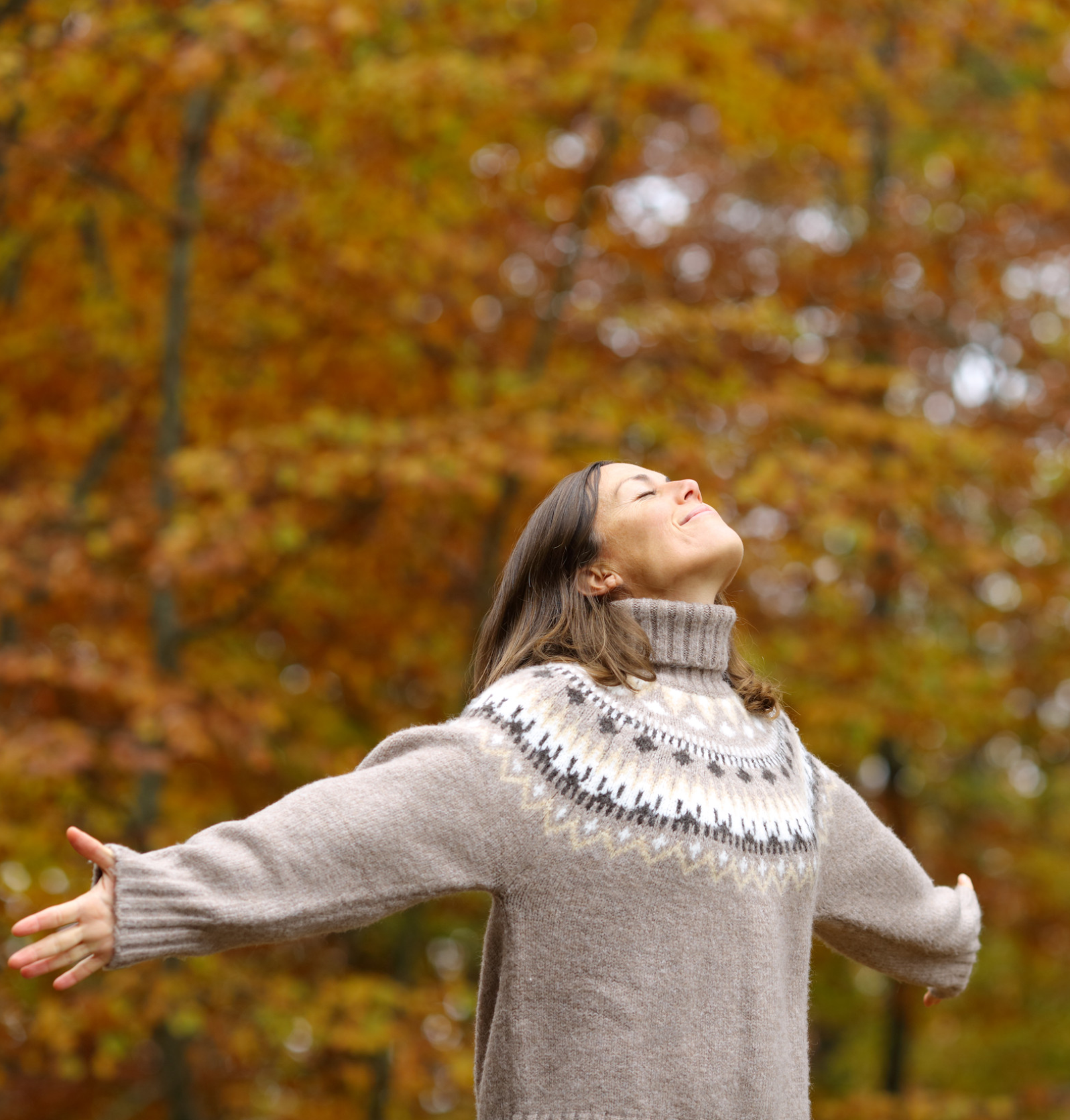 Middle age woman stretching arms breathing fresh air in a forest in autumn