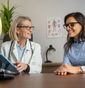A healthcare professional in a white coat discusses with a patient in a well-lit office, surrounded by medical charts and a plant A healthcare professional in a white coat discusses with a patient in a well-lit office, surrounded by medical charts and a plant